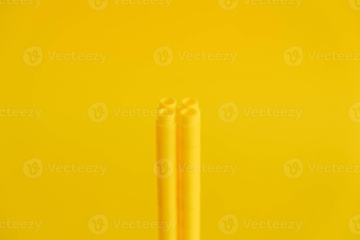 Yellow plastic building blocks in shape of a tower on yellow background photo