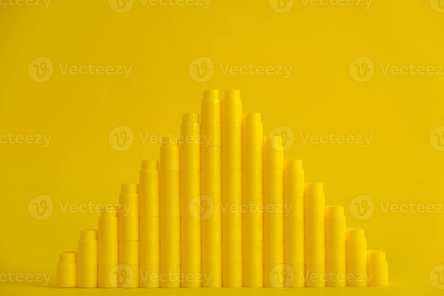 Yellow plastic building blocks in shape of a pyramid on yellow background photo