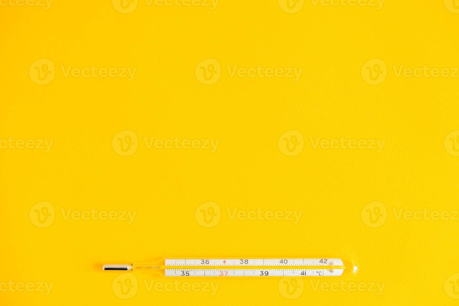 Medical mercury thermometer on a yellow background photo