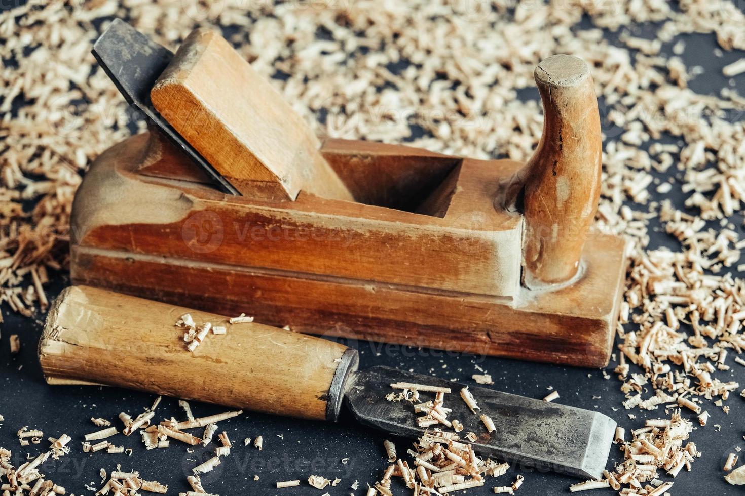 Plano de mano antiguo y cincel con virutas de madera sobre fondo negro. herramienta de mano de carpintería antigua foto