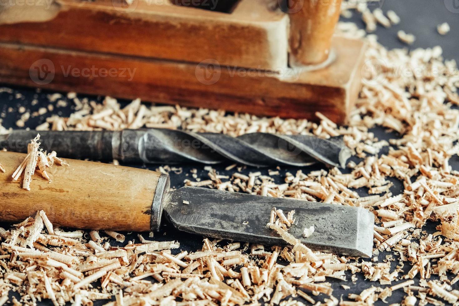 Plano de mano antiguo, taladro y cincel con virutas de madera sobre fondo negro. herramienta de mano de carpintería antigua foto