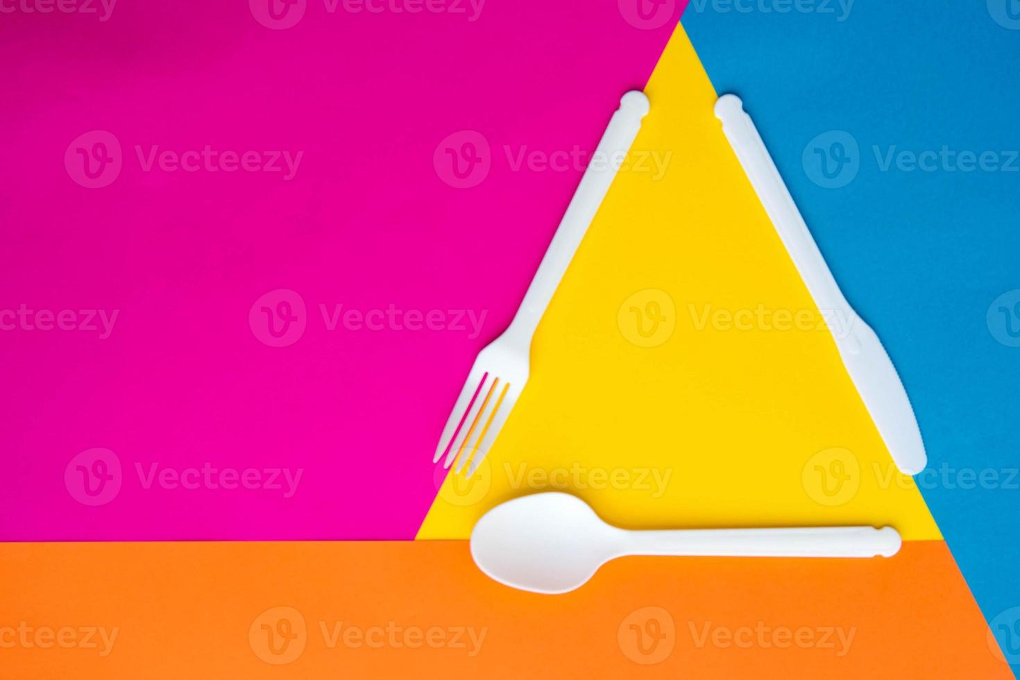 Plastic white fork, knife and spoon on multicolored background. Cooking utensil photo