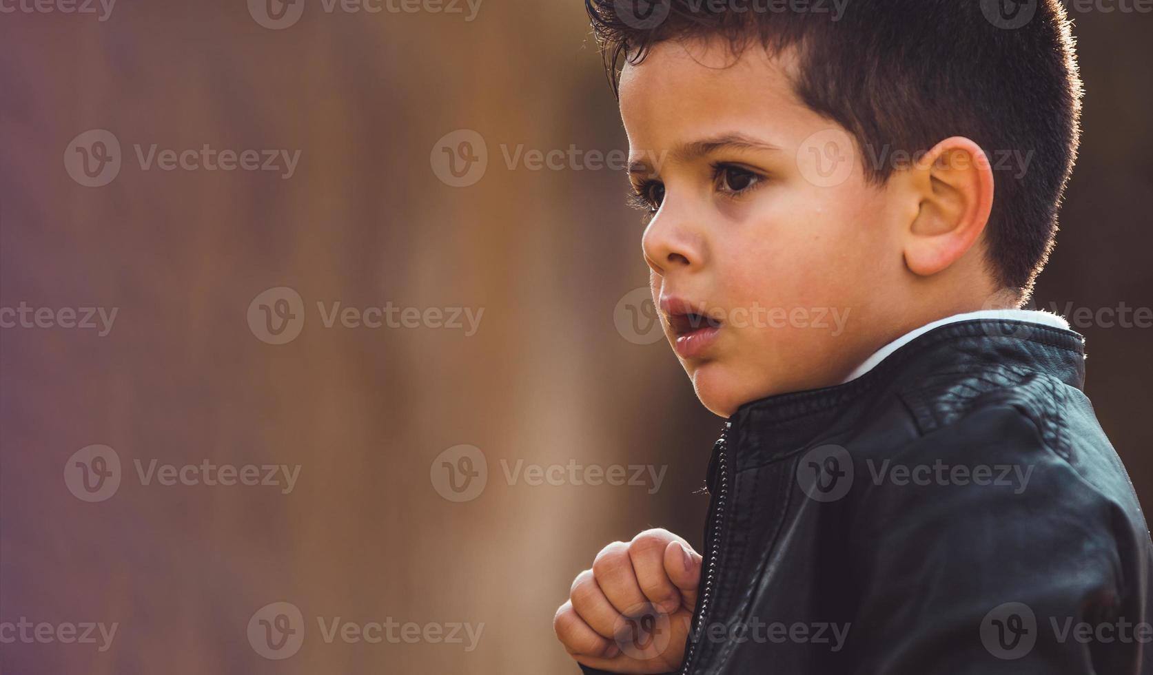 Fashion little boy wearing a leather jacket. Park or forest, outdoor photo