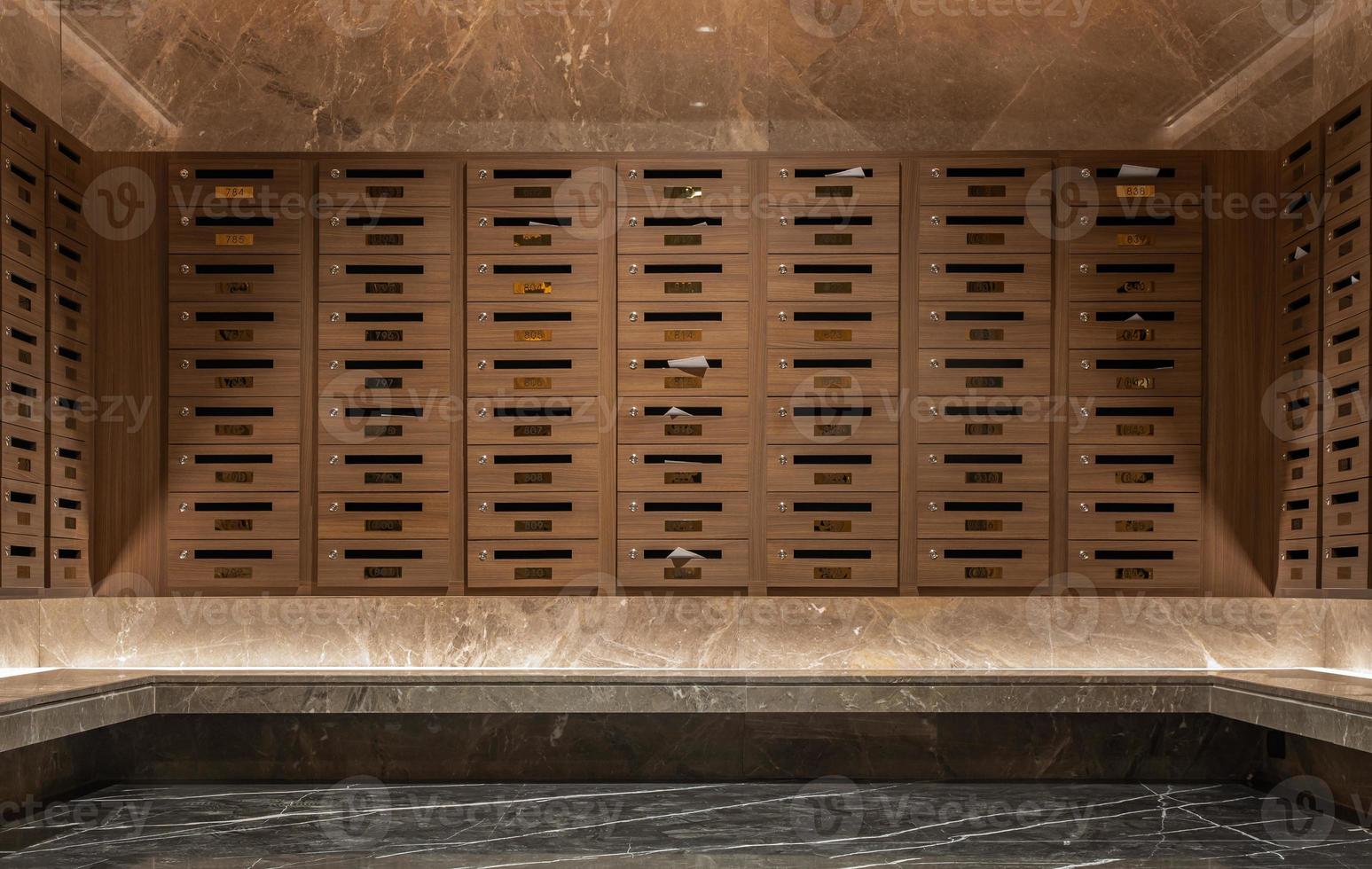 Many mail boxes made from brown wood were placed on first floor in condo. photo