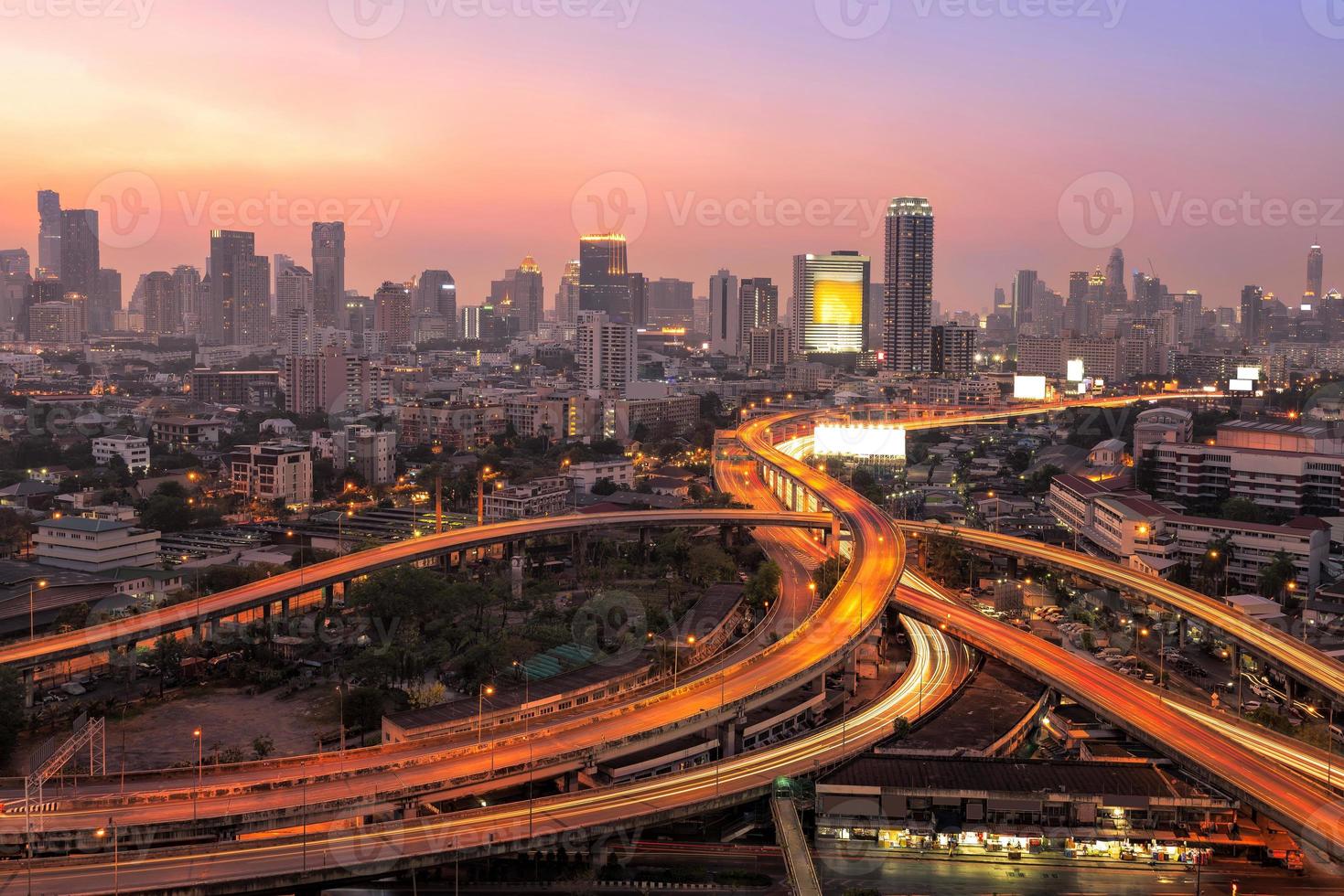 edificios de oficinas modernos, condominio en el centro de la gran ciudad con autopista, autopista, autopista la infraestructura para el transporte en la ciudad moderna, vista urbana en el momento del crepúsculo foto