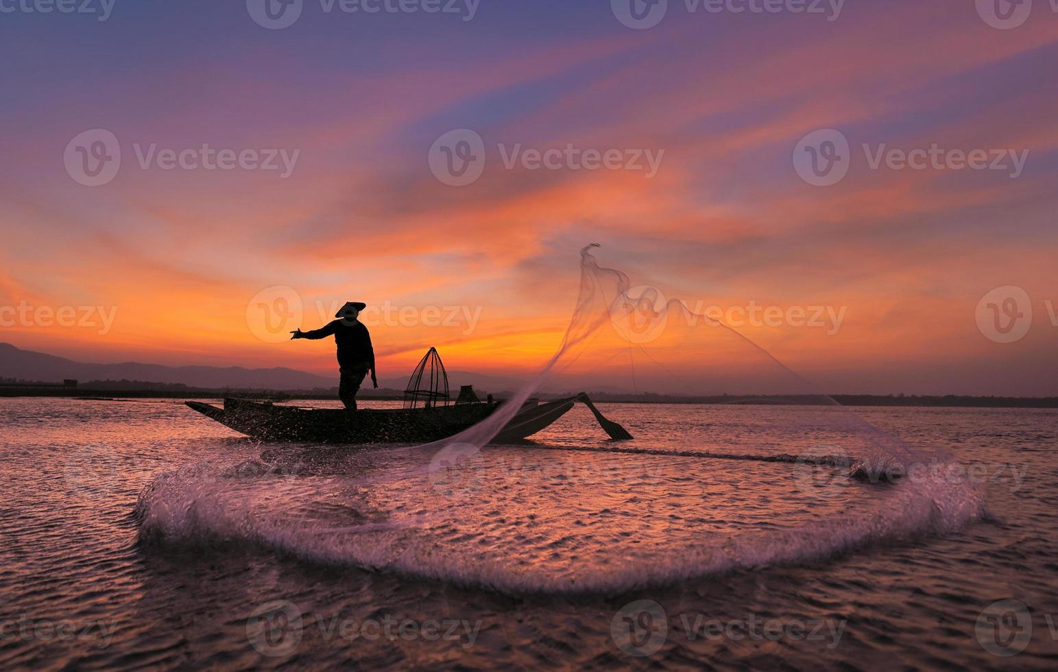 Asian fisherman on wooden boat casting a net for catching freshwater fish  in nature river in the early morning before sunrise 4953798 Stock Photo at  Vecteezy