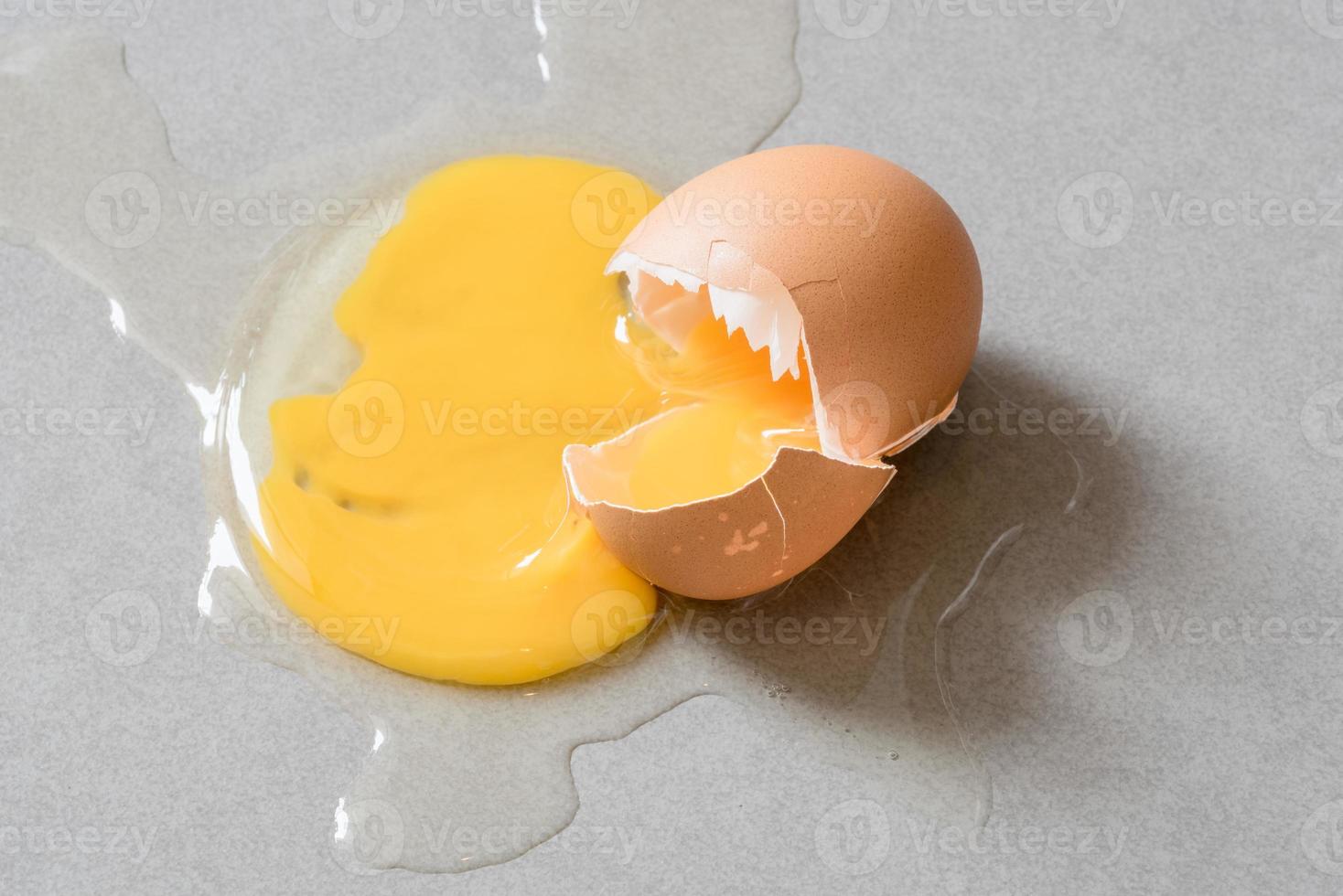 Egg drop crack splattered down on ceramic tile. Abstract macro with shallow and depth of field effect photo