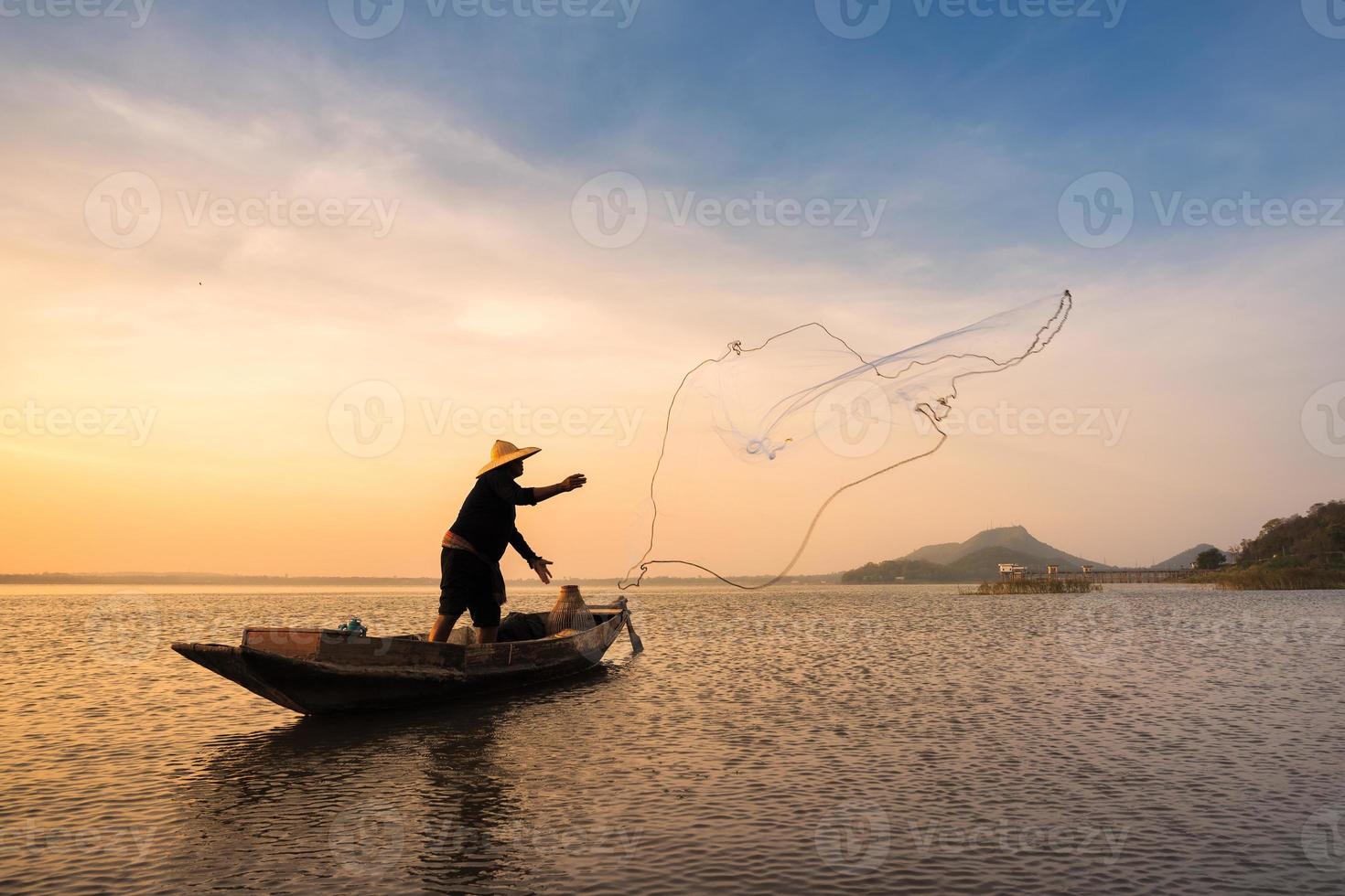 Pescador asiático con su bote de madera en el río de la naturaleza temprano en la mañana antes del amanecer foto