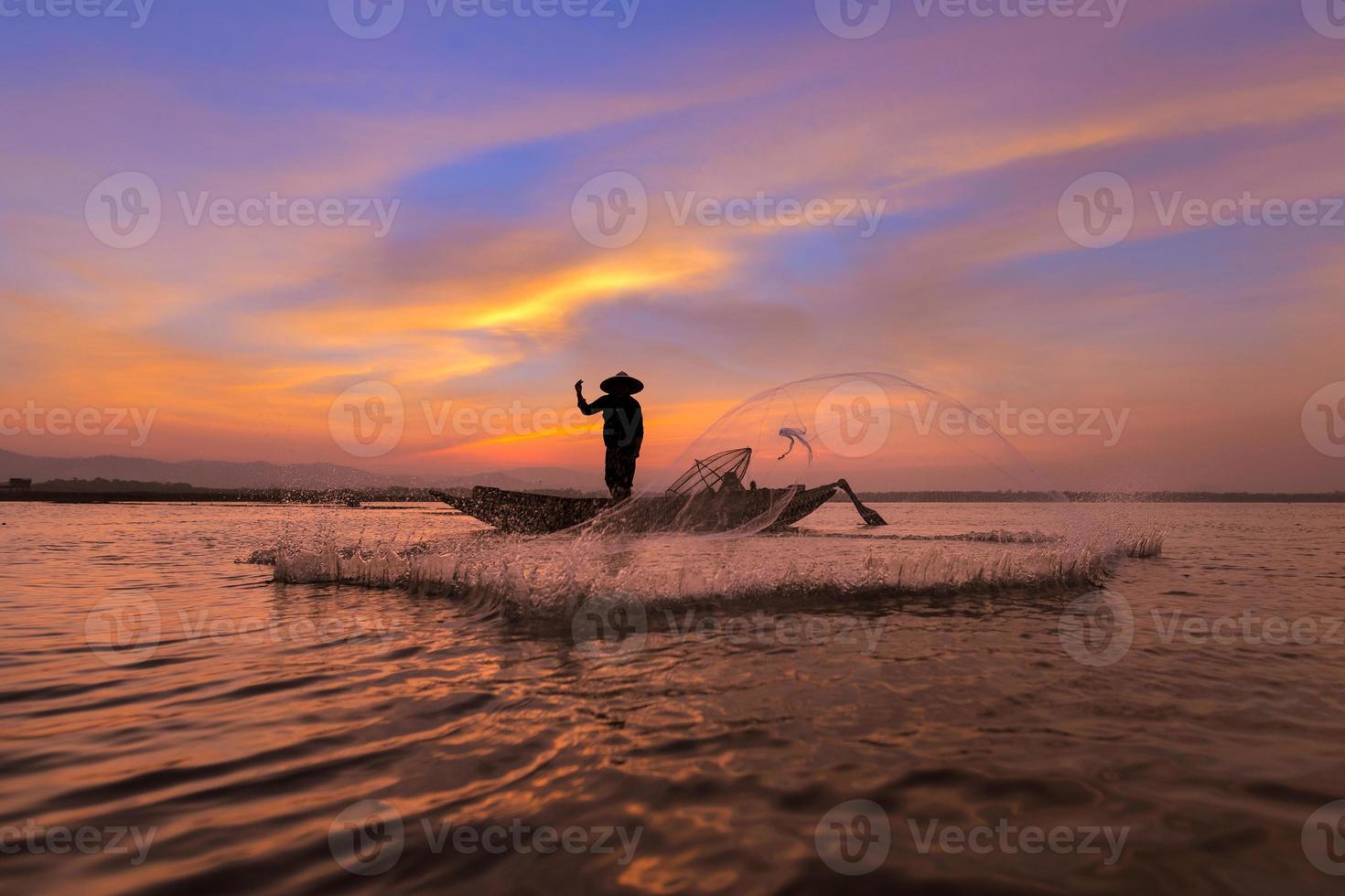 Asian fisherman with his wooden boat in nature river at the early morning before sunrise photo