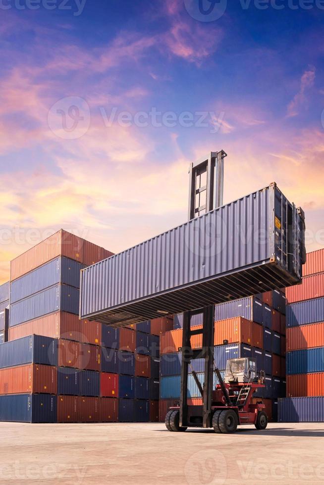 Forklift truck lifting cargo container in shipping yard or dock yard against sunrise sky with cargo container stack in background for transportation import,export and logistic industrial concept photo