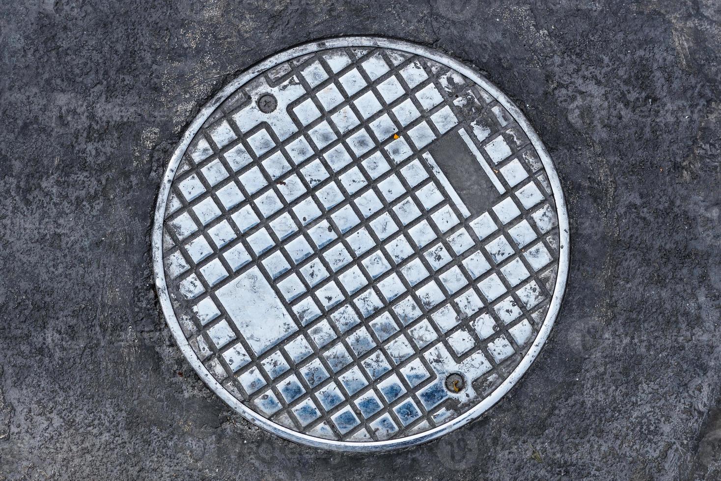 Closeup photo of Old Sewer manhole cover on the urban road.