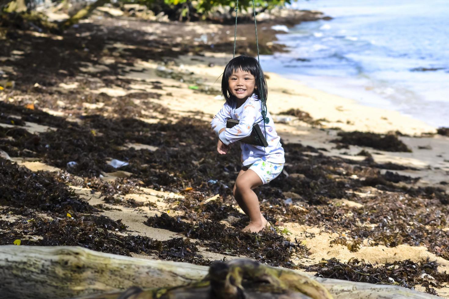 niña pequeña jugando en un columpio en la playa foto