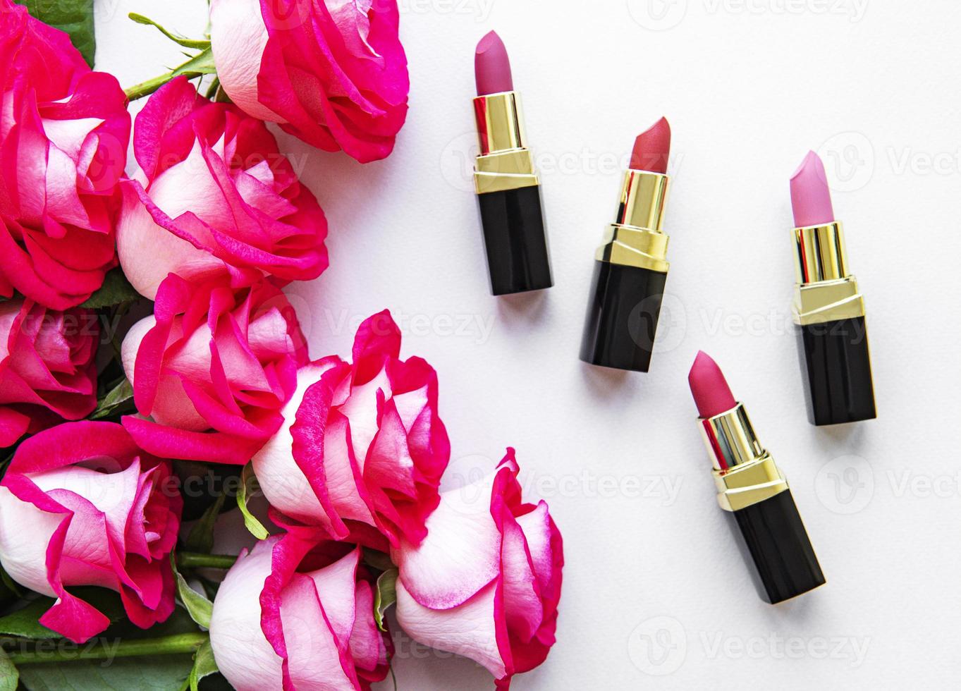 lápices labiales y rosas rojas foto