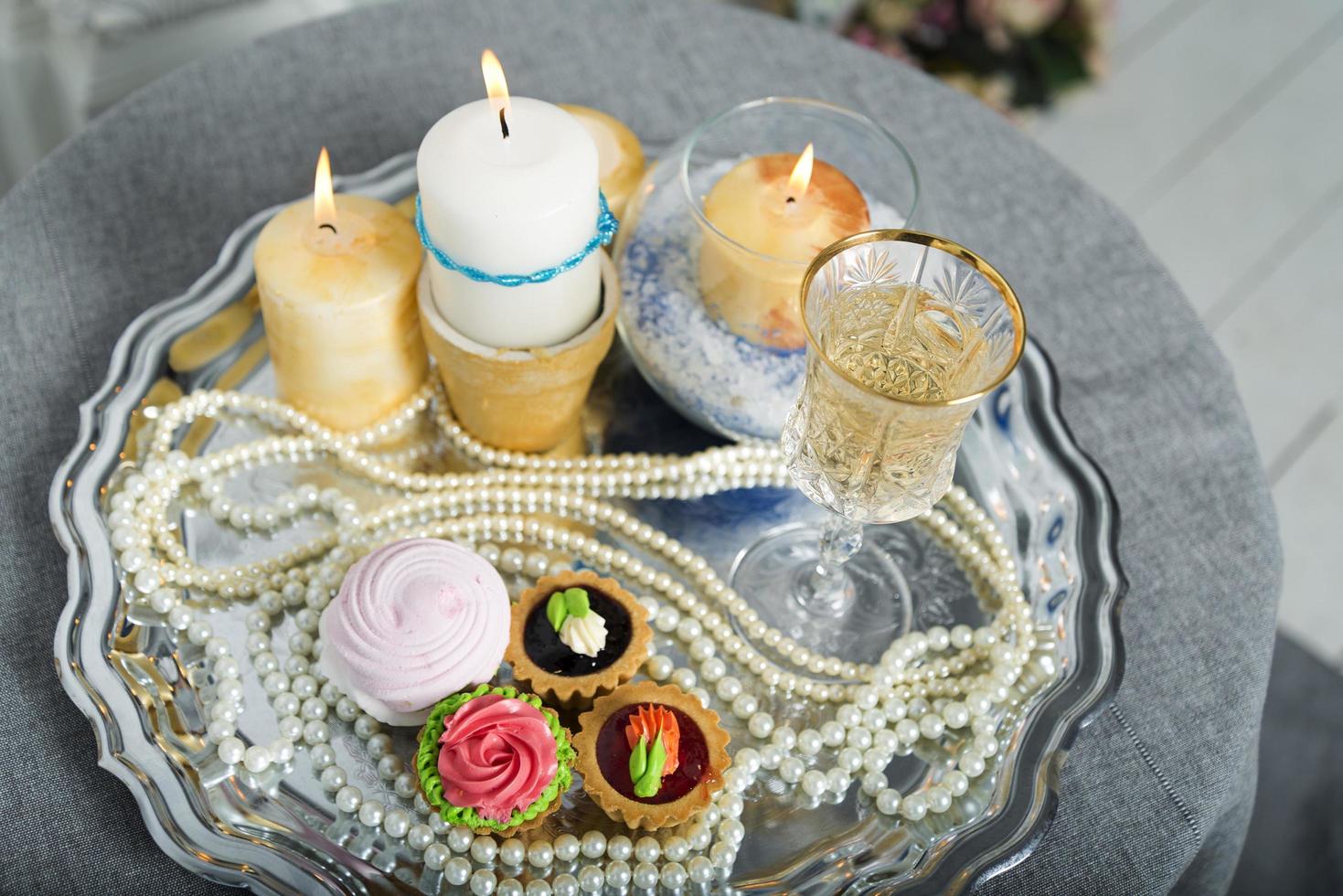 velas, pastel, perlas en una bandeja de plata. foto