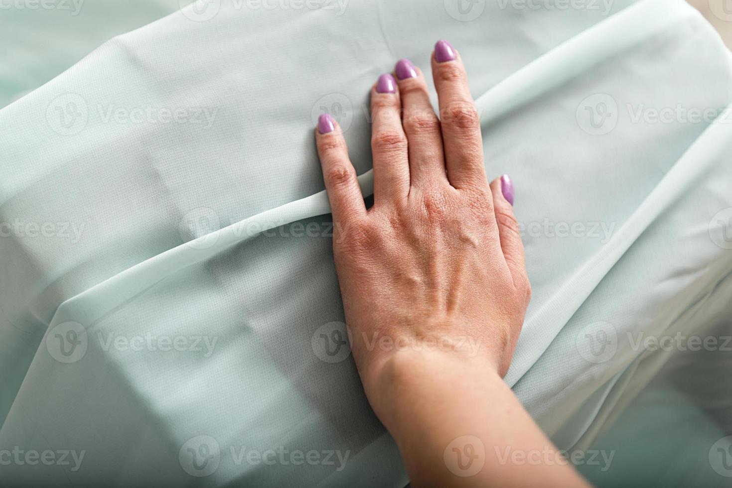 Female hand on the turquoise fabric. photo