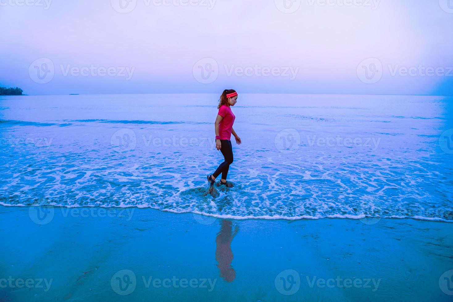 Woman jogging workout on the beach in the morning. Relax with the sea walk. in summer photo