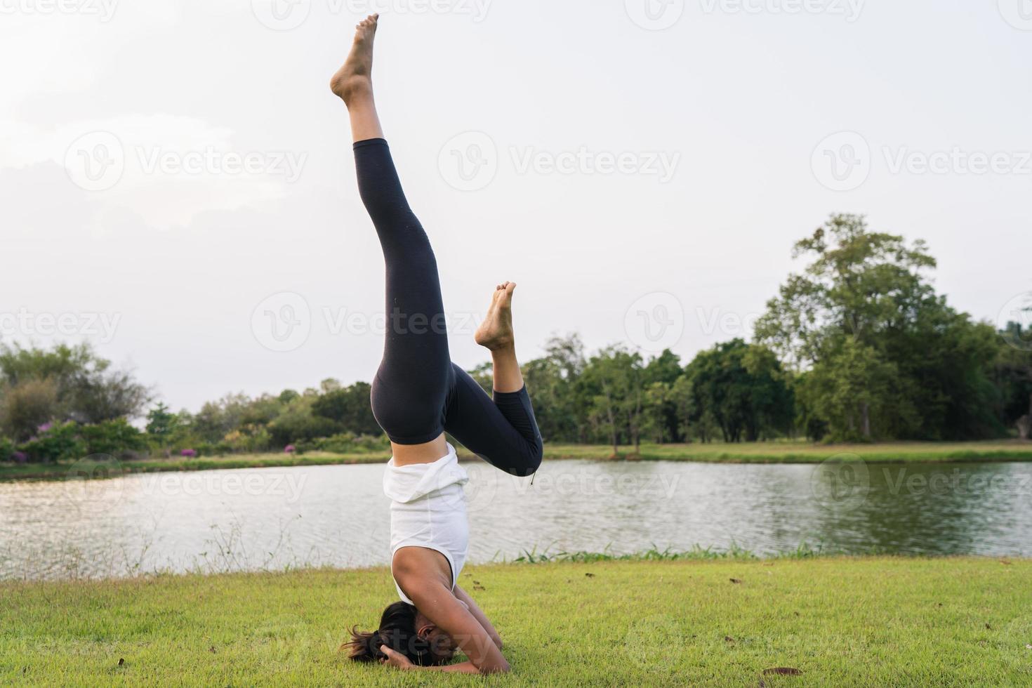 Young asian woman yoga outdoors keep calm and meditates while practicing yoga to explore the inner peace. Yoga have good benefits for health near lake at park. Sport and Healthy lifestyle concept. photo