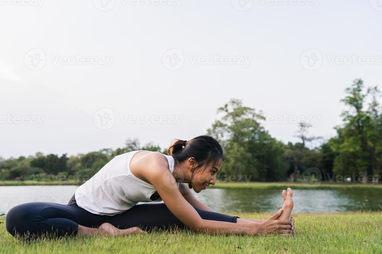 Young asian woman yoga outdoors keep calm and meditates while practicing yoga to explore the inner peace. Yoga have good benefits for health near lake at park. Sport and Healthy lifestyle concept. photo