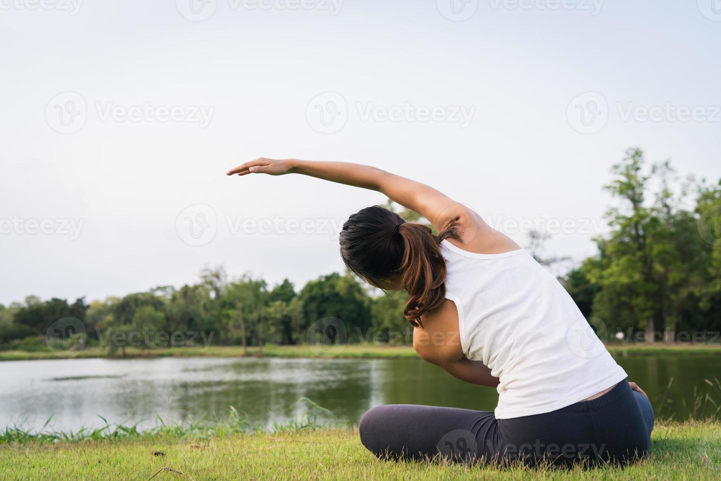 joven mujer asiática yoga al aire libre mantén la calma y medita mientras practicas yoga para explorar la paz interior. El yoga tiene buenos beneficios para la salud cerca del lago en el parque. concepto de deporte y estilo de vida saludable. foto
