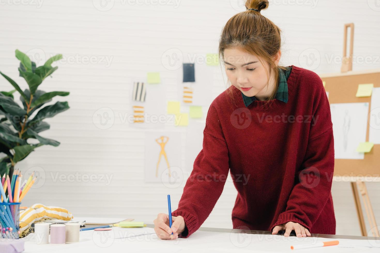 Professional beautiful Asian female fashion designer working with fabric sketches and drawing clothing design at the studio. Lifestyle women working concept. photo