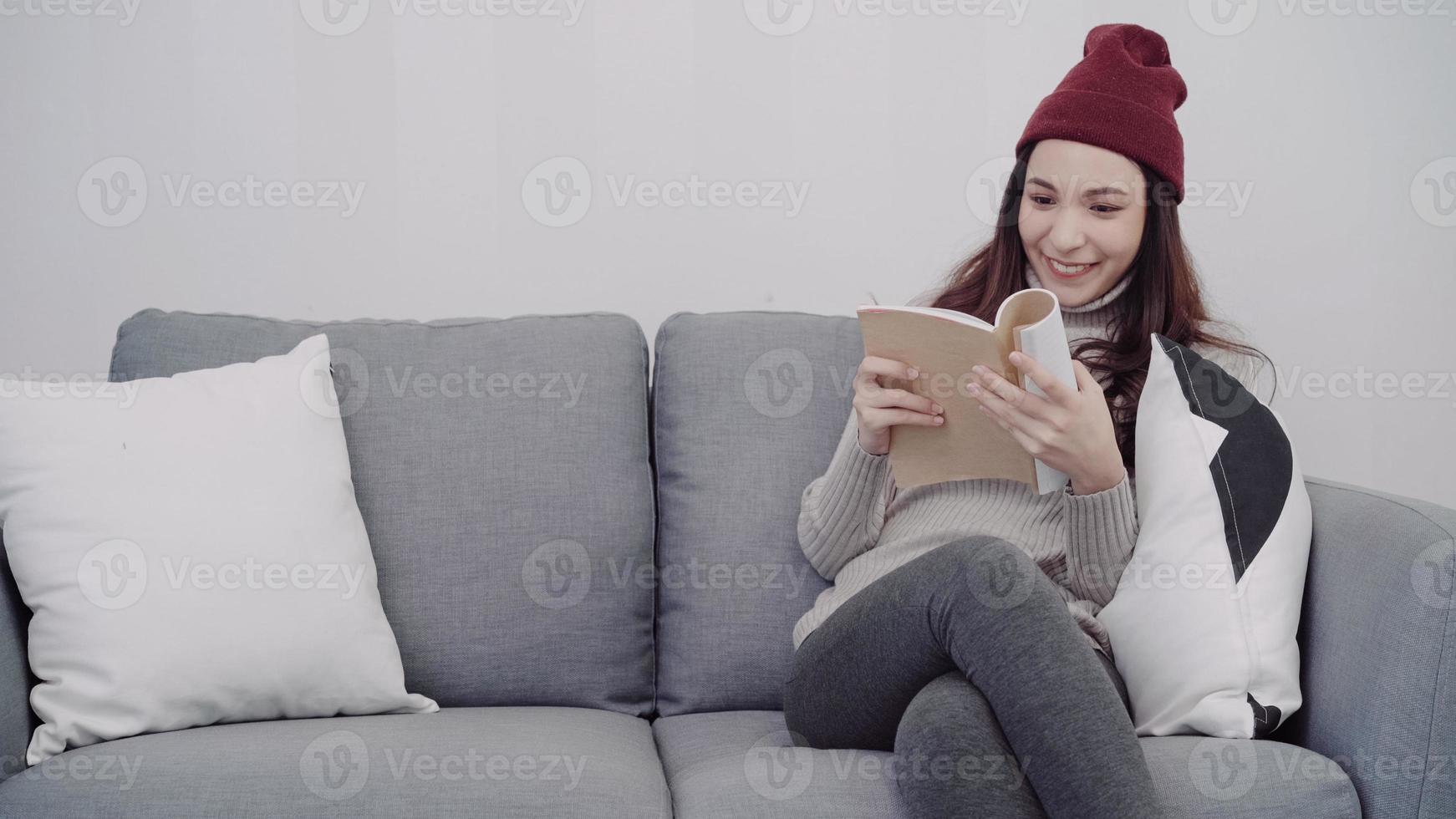 Portrait of beautiful attractive Asian woman reading a book while sitting on the sofa when relax in living room at home. Lifestyle women at home in Christmas and New year holidays concept. photo