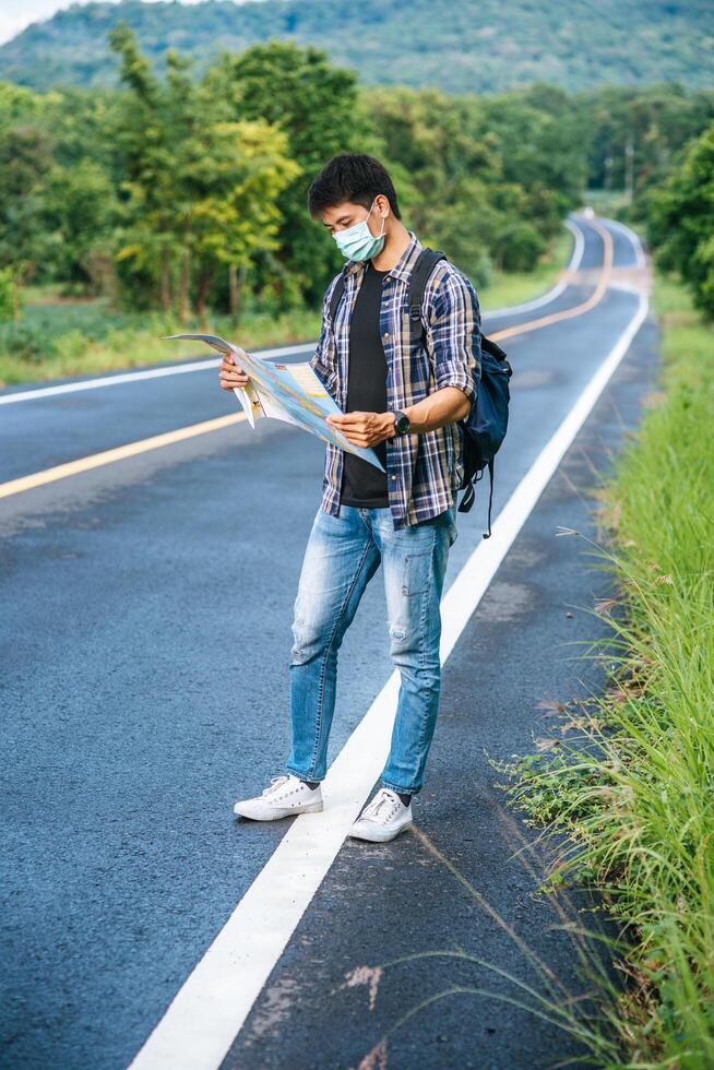 Male tourists stand and look at the map on the road. photo