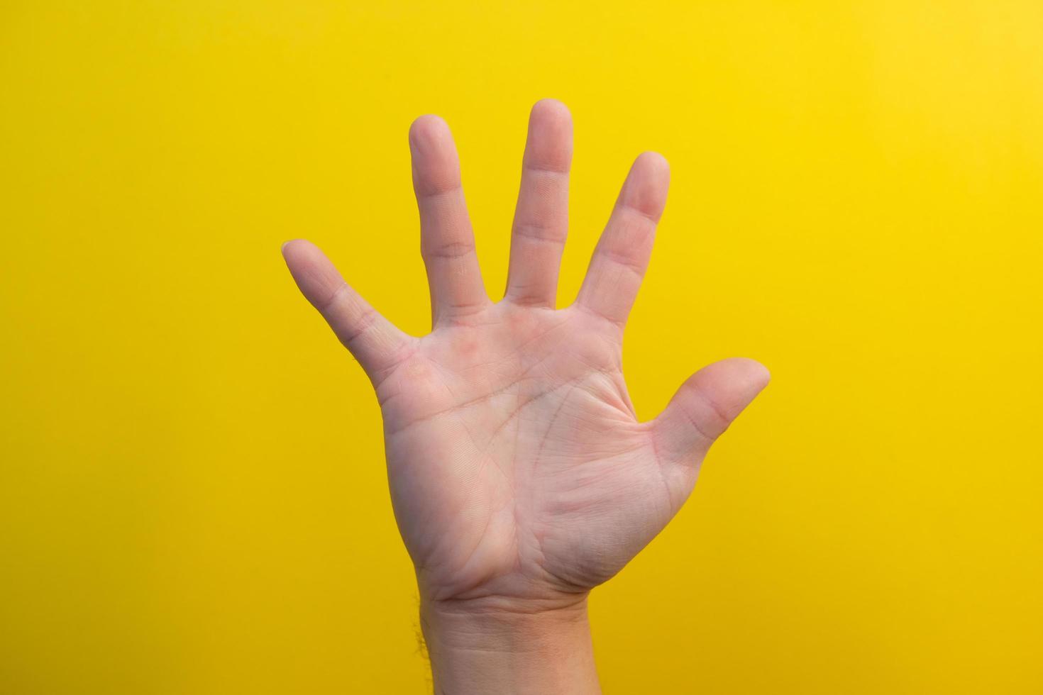 Man hand extended in greeting isolated on yellow background. Number five. photo