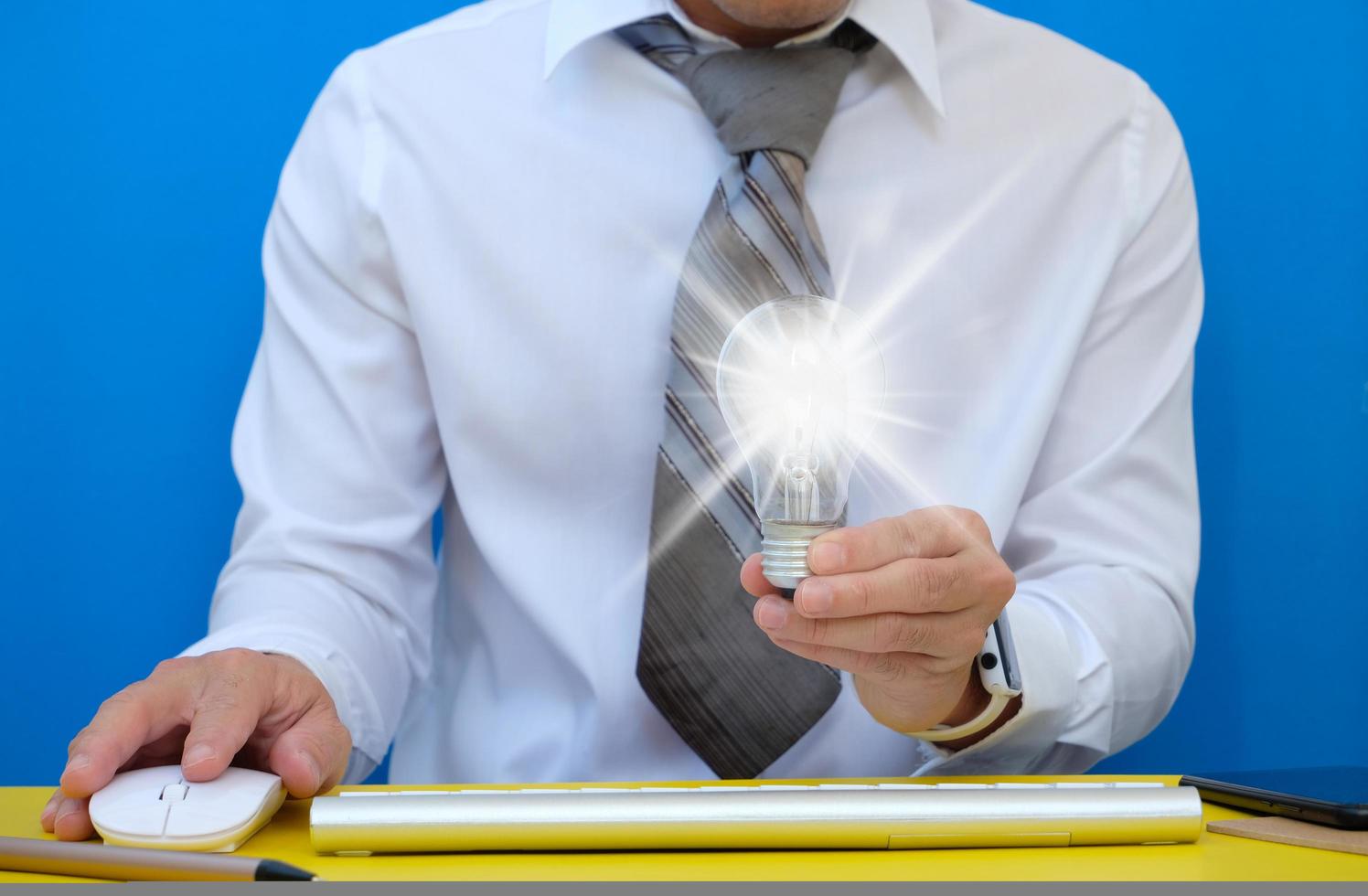 Hand of businessman holding illuminated light bulb on yellow background. idea, innovation and inspiration concept. The concept of the business idea photo