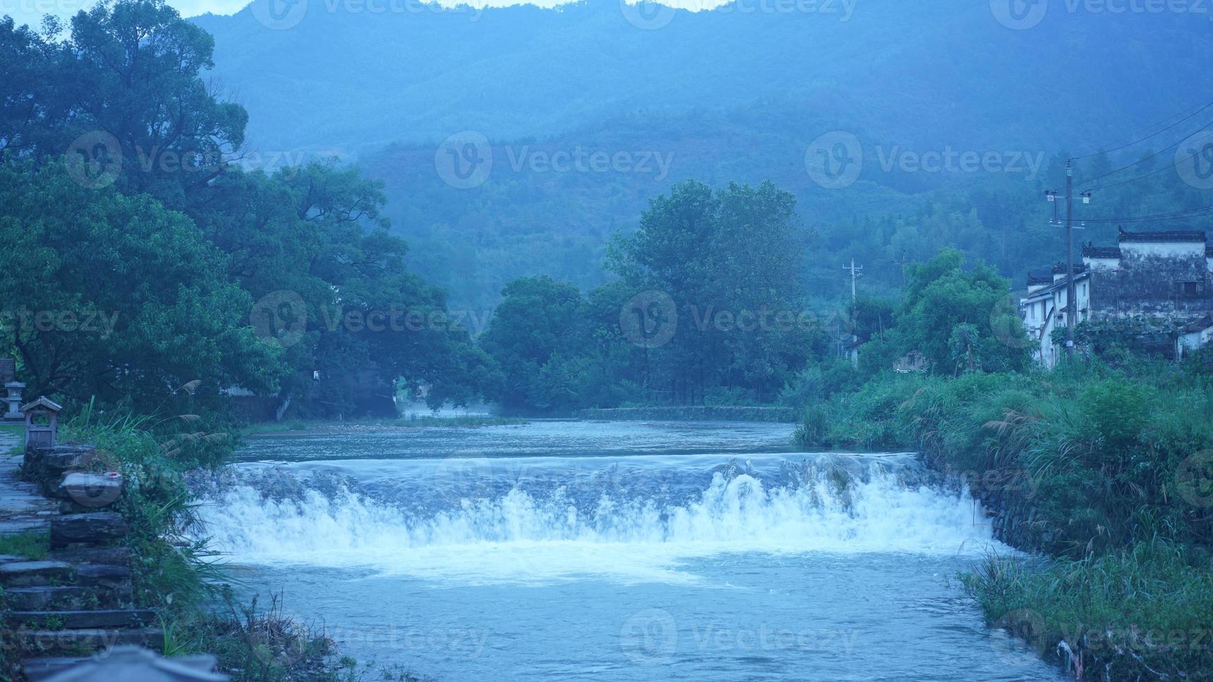 The beautiful countryside view with the waterfall flowing in the mountains after the rainy day photo