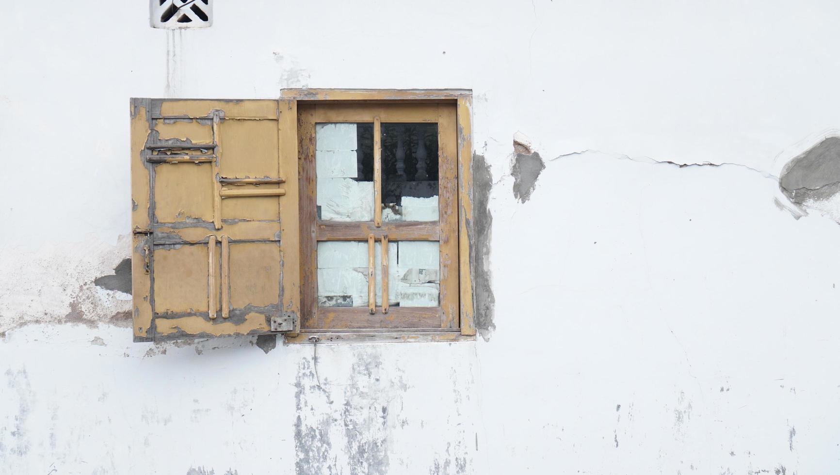 Ventana de madera vieja en una pared blanca dañada foto