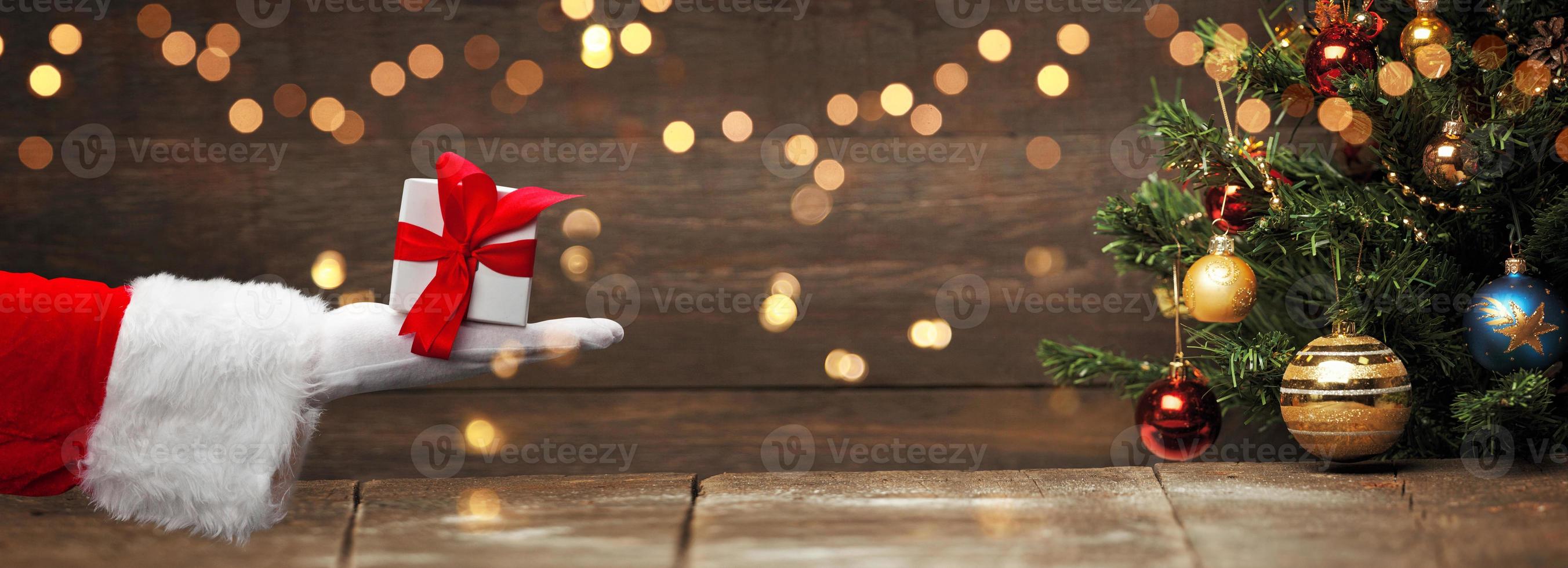 mano de santa claus sosteniendo un regalo de navidad envuelto. foto