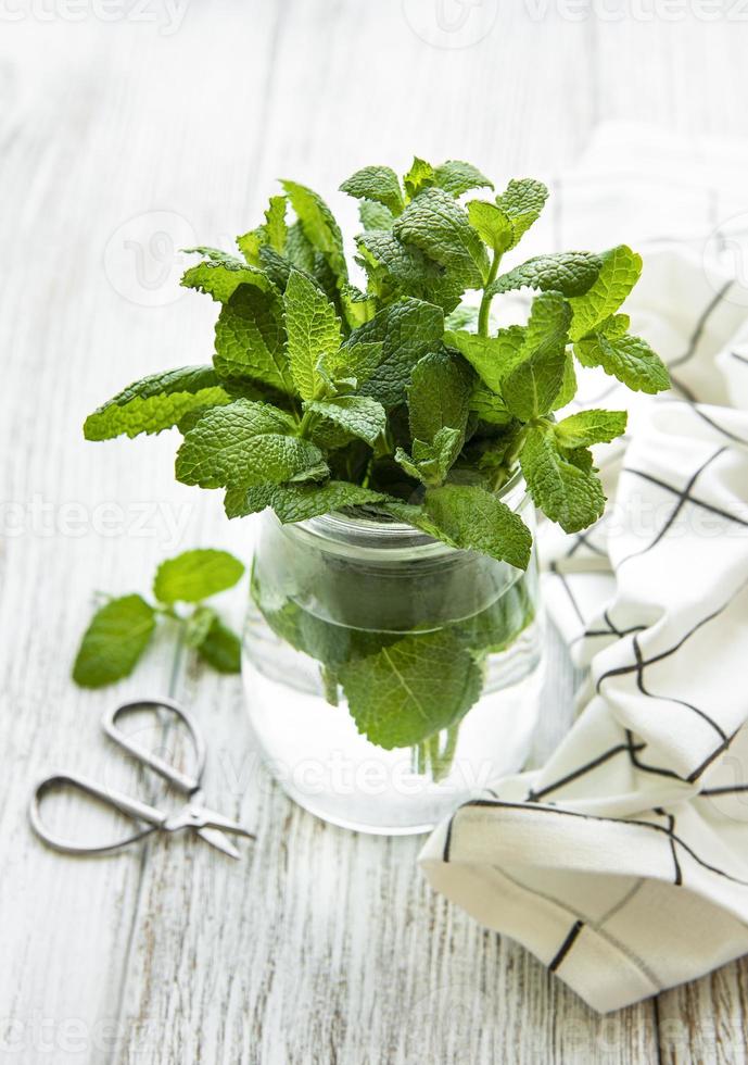 hojas de menta fresca en un frasco de vidrio pequeño foto