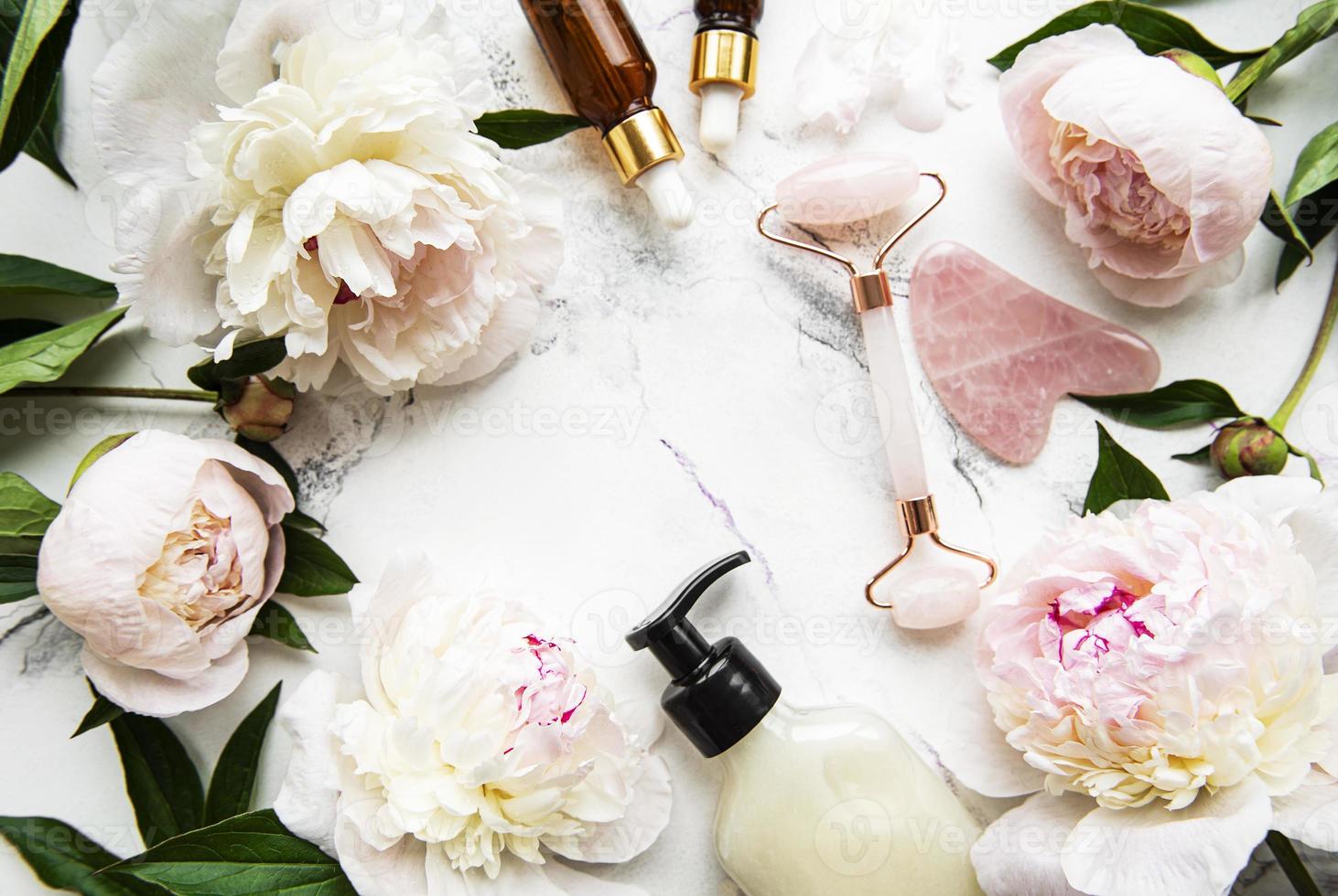 Jade face roller and massage oils with pink peonies photo