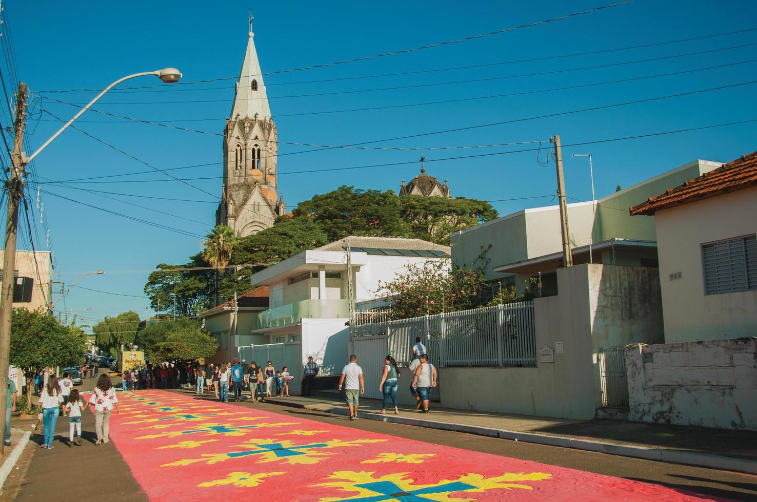 Sao Manuel, Brazil - May 31, 2018. People walking on street and admiring colorful sand carpets made for the celebration of Holy Week of Sao Manuel. A little town in the countryside of Sao Paulo State. photo