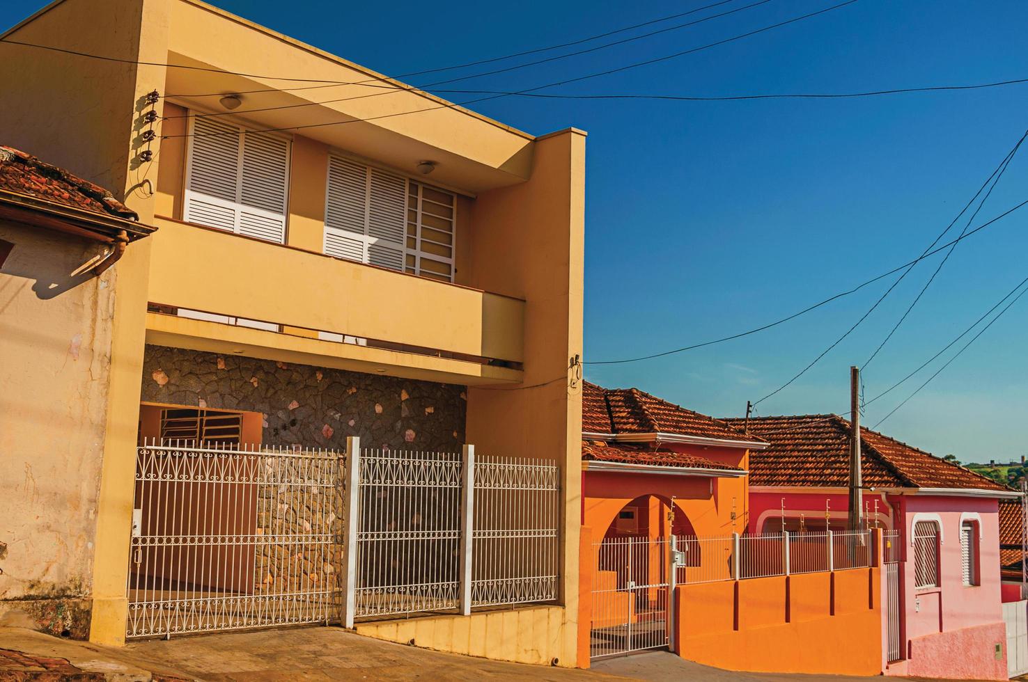 Sao Manuel, Brazil, October 14, 2017. Working-class colored houses and fences in an empty street on a sunny day at Sao Manuel. A cute little town in the countryside of Sao Paulo State. photo