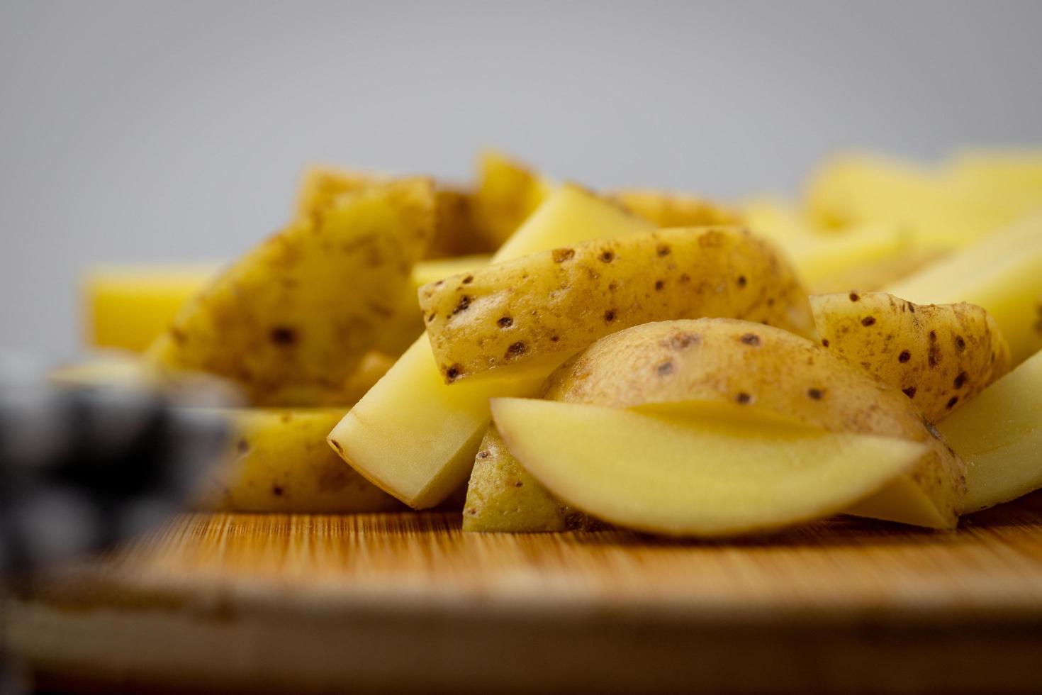 patatas crudas cortadas en patatas fritas sobre una tabla de madera. foto