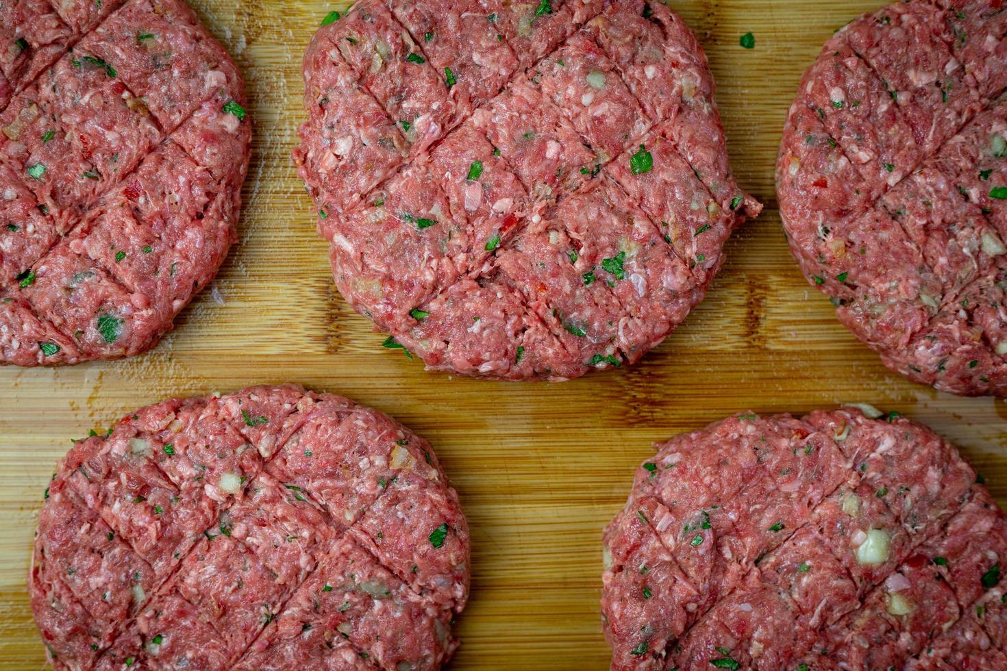 Raw beef prepared for burgers. Seasoned meat on a wooden board. Top view. photo