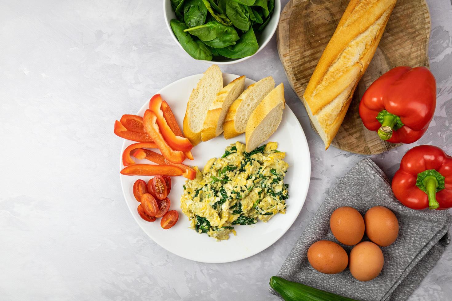 Scrambled eggs with spinach and fresh bread. Delicious diet breakfast. Top view. photo