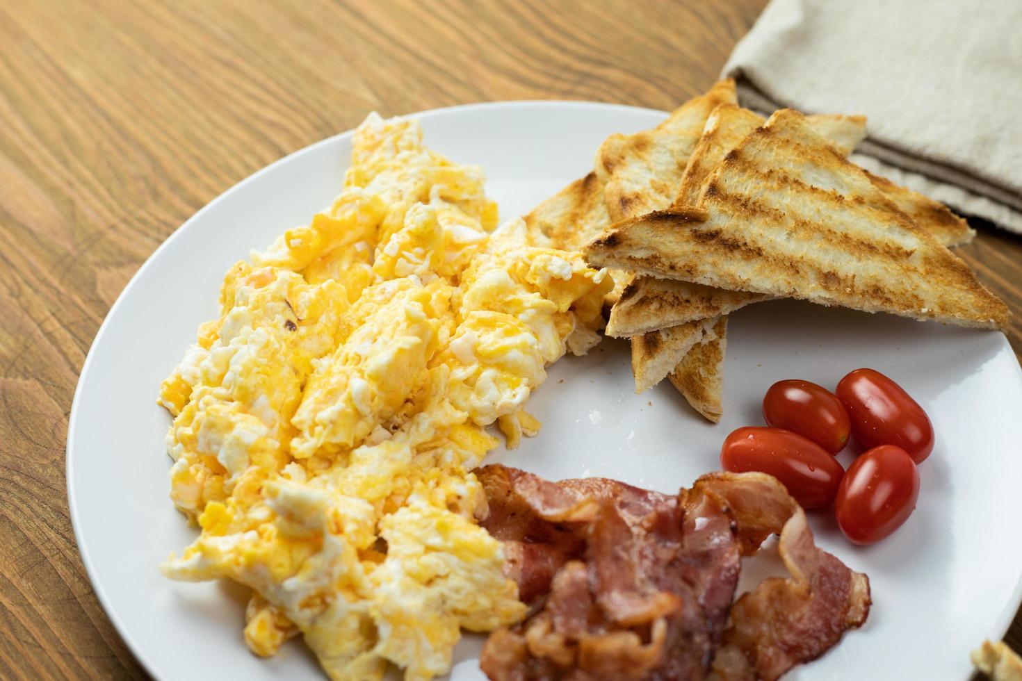 Scrambled eggs with bacon and grilled bread. Delicious breakfast. photo