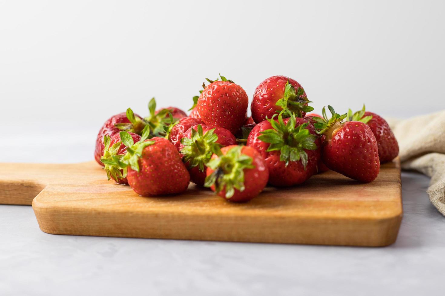 fresas enteras sobre una tabla de madera. Fondo blanco. foto