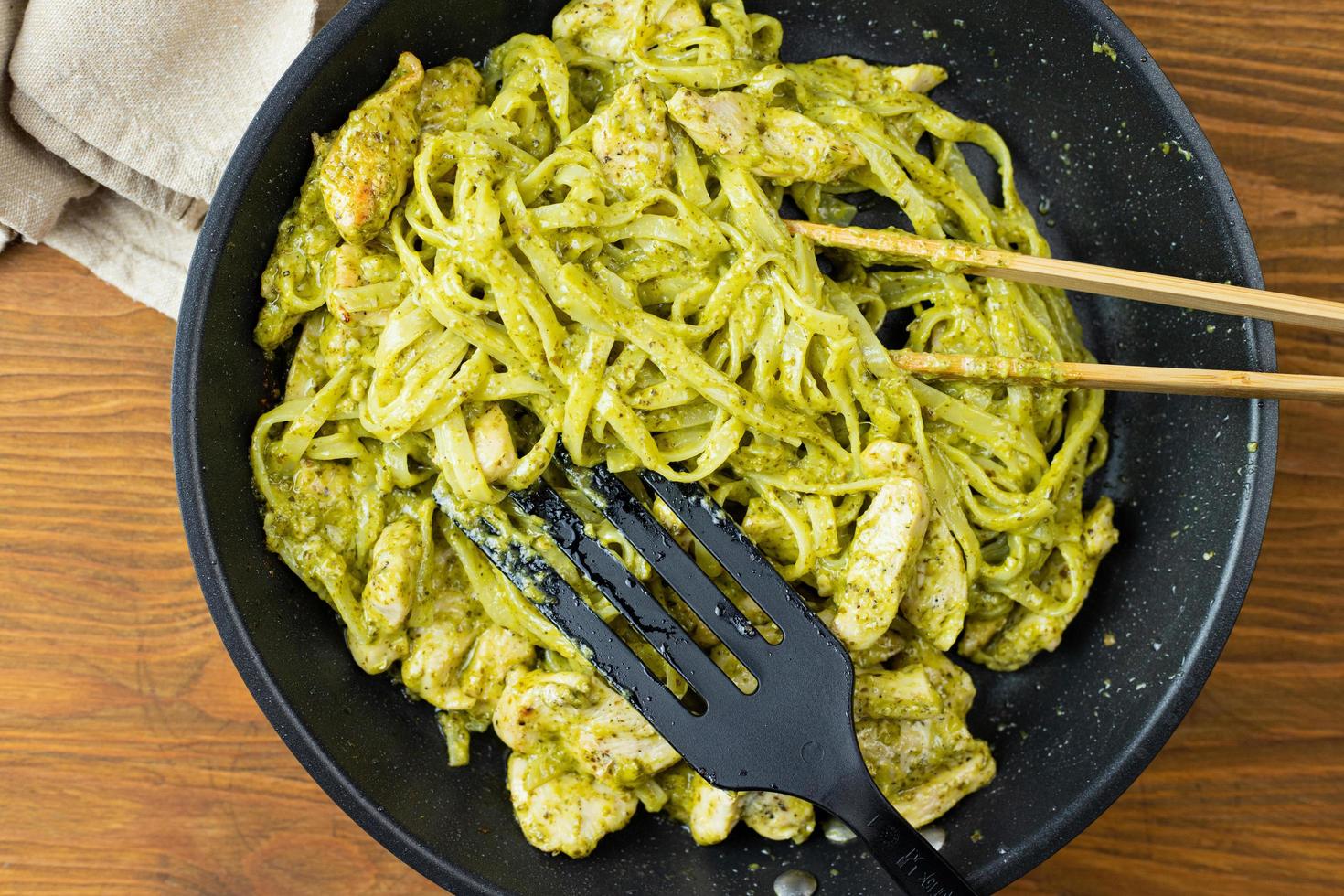 Pasta with pieces of chicken and basil pesto prepared in a pan. photo