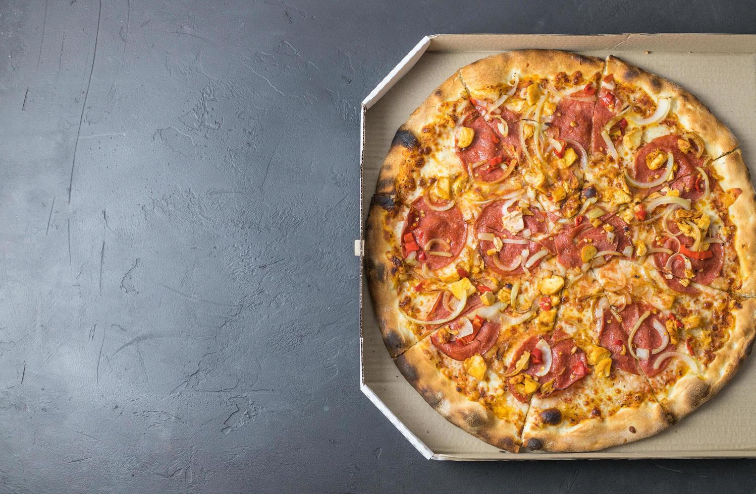 Fresh pizza in a box on a dark background. Place for text. photo