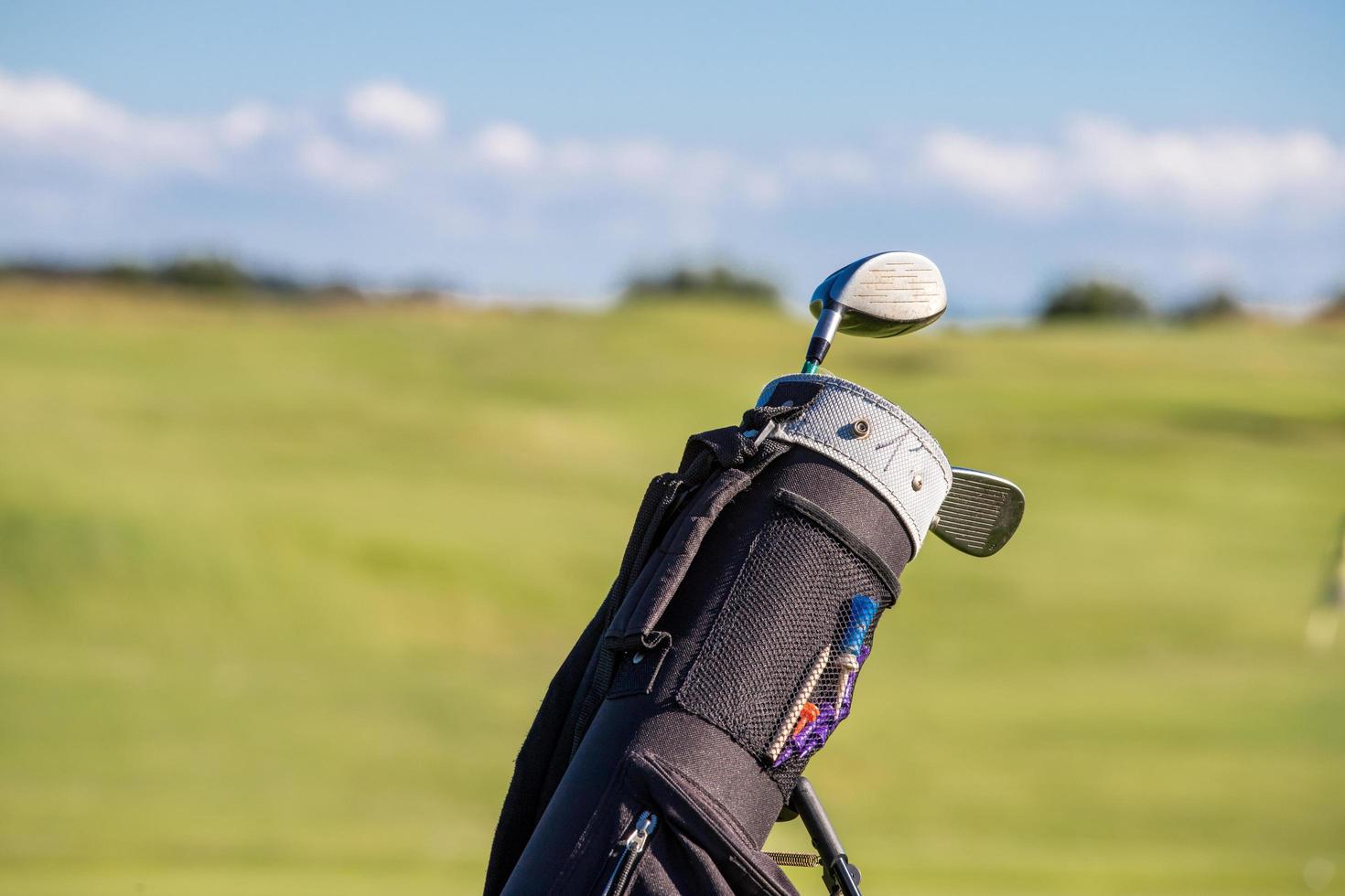 Palos de golf en una bolsa en el fondo del campo de golf concepto de golf foto