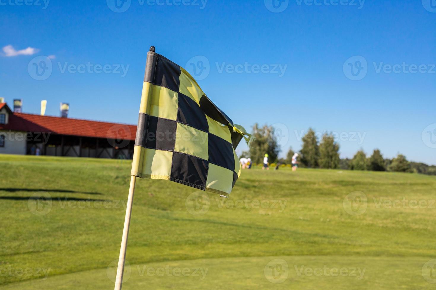 A checkered flag on a golf course signifying a hole against gold building photo
