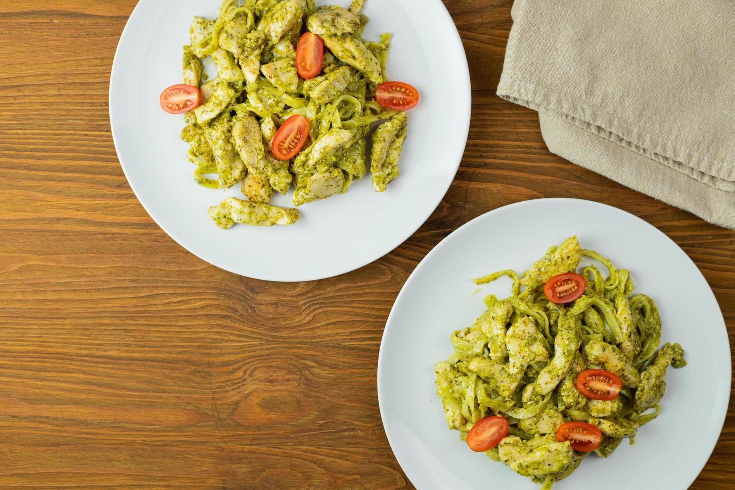 Pasta with pieces of chicken, basil pesto, and tomatoes. Delicious dinner. photo
