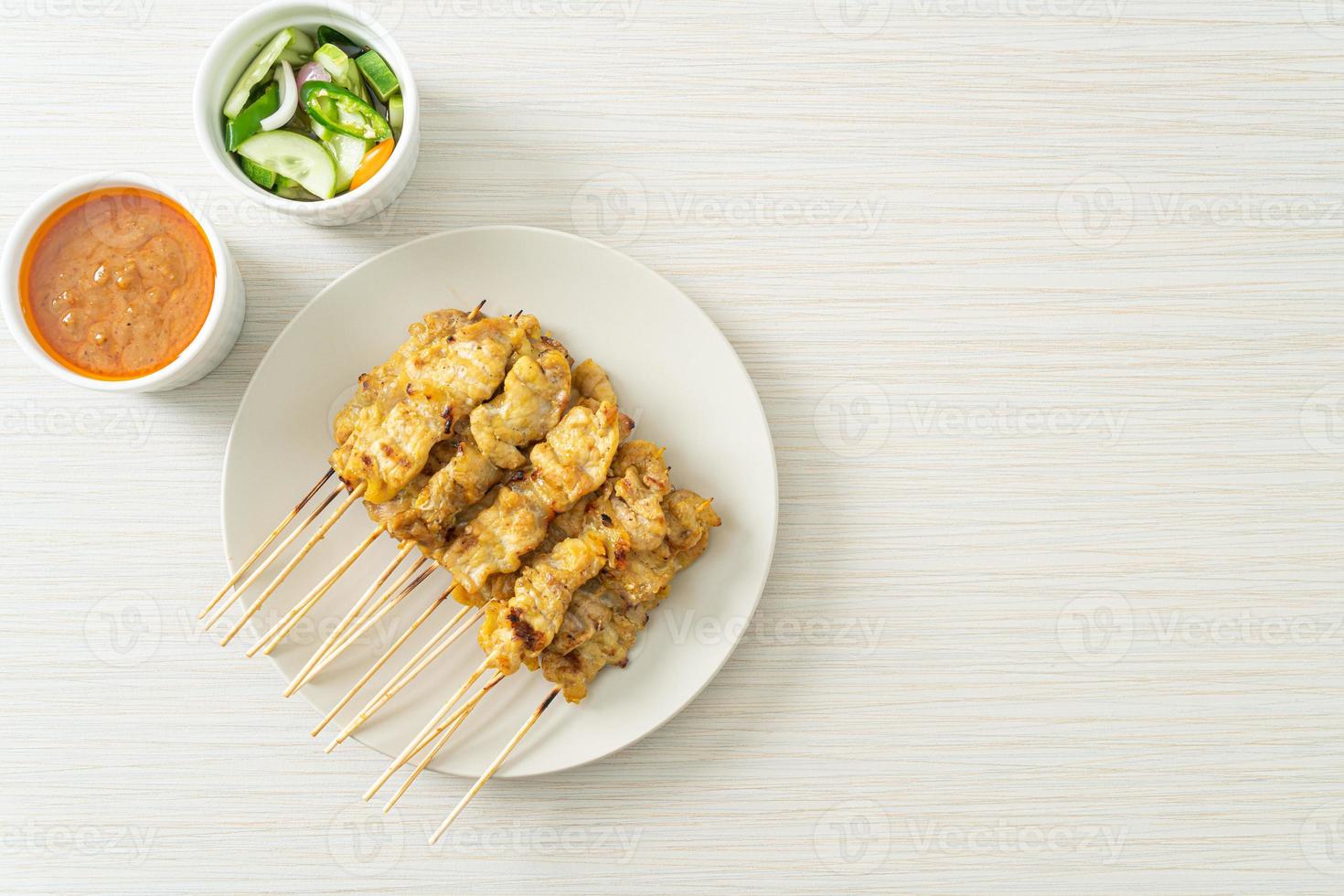 Pork satay with peanut sauce pickles which are cucumber slices and onions in vinegar photo