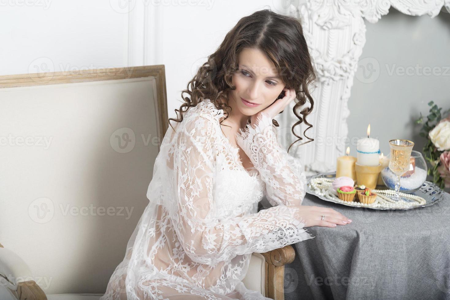 Girl in a white dress sitting at a table photo