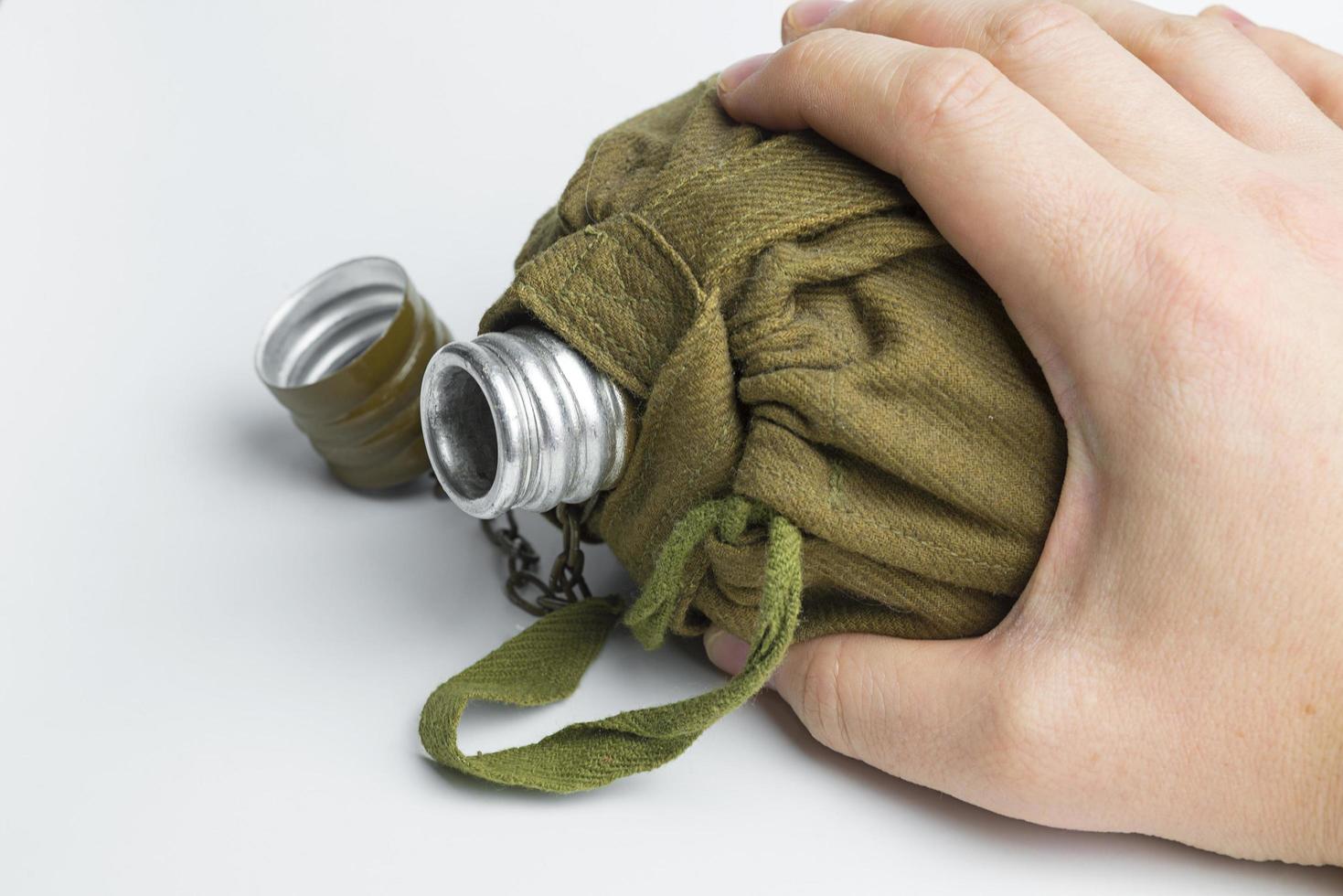 Hand holding military flask on white background. photo