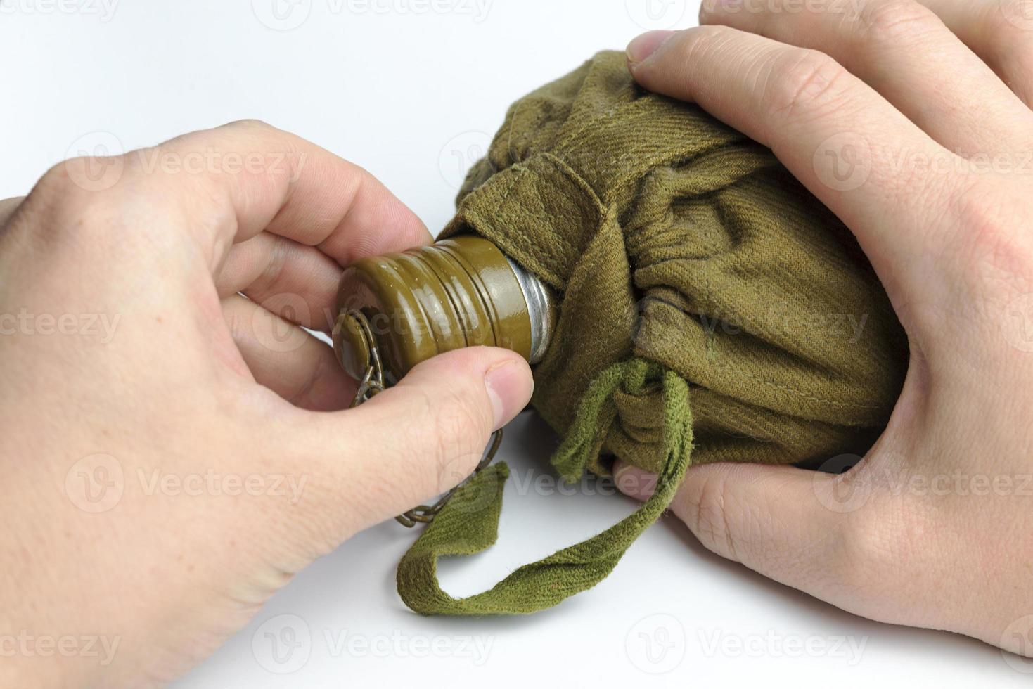 Hand holding military flask on white background. photo