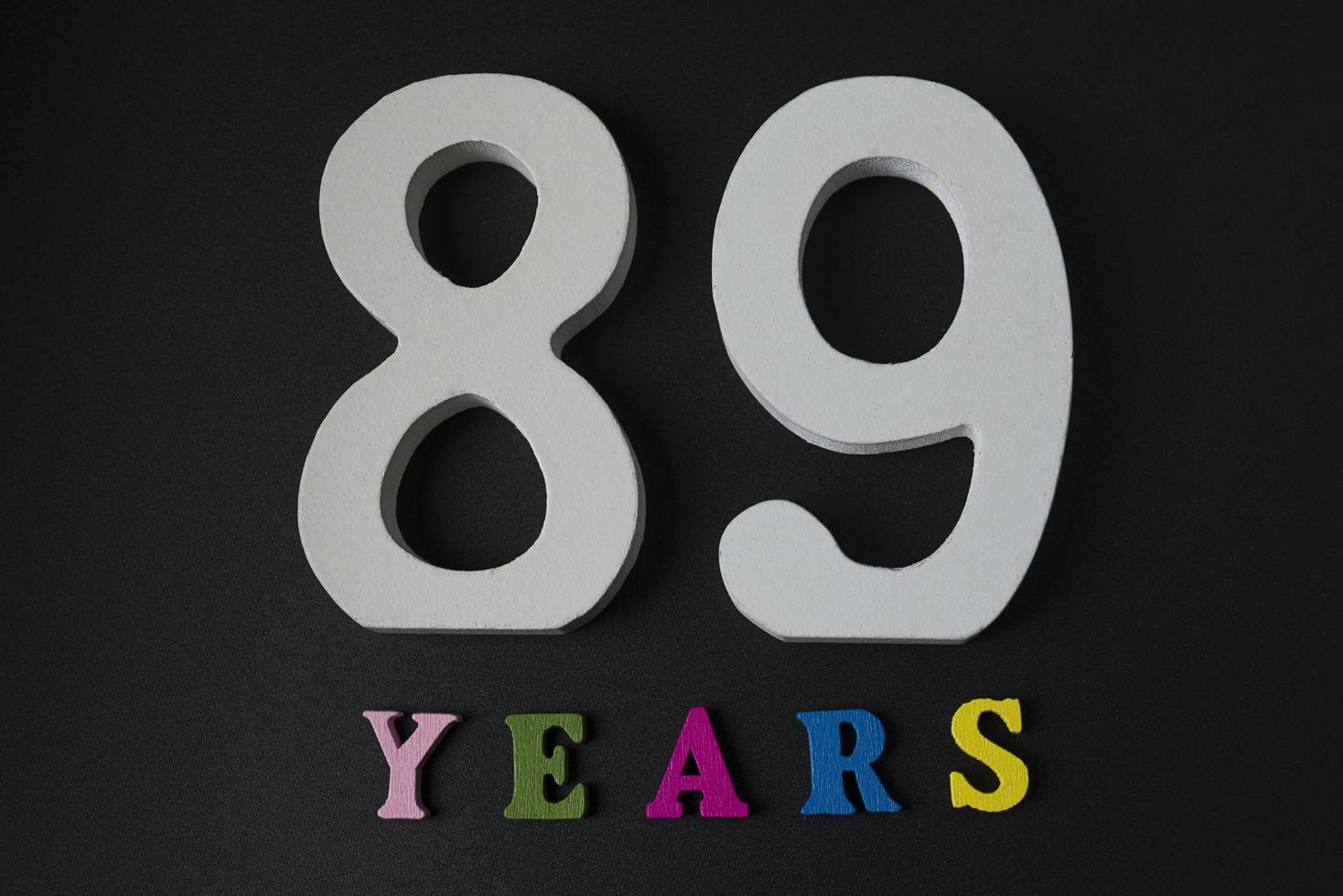 Letters and numbers eighty-nine years old on a black background. photo
